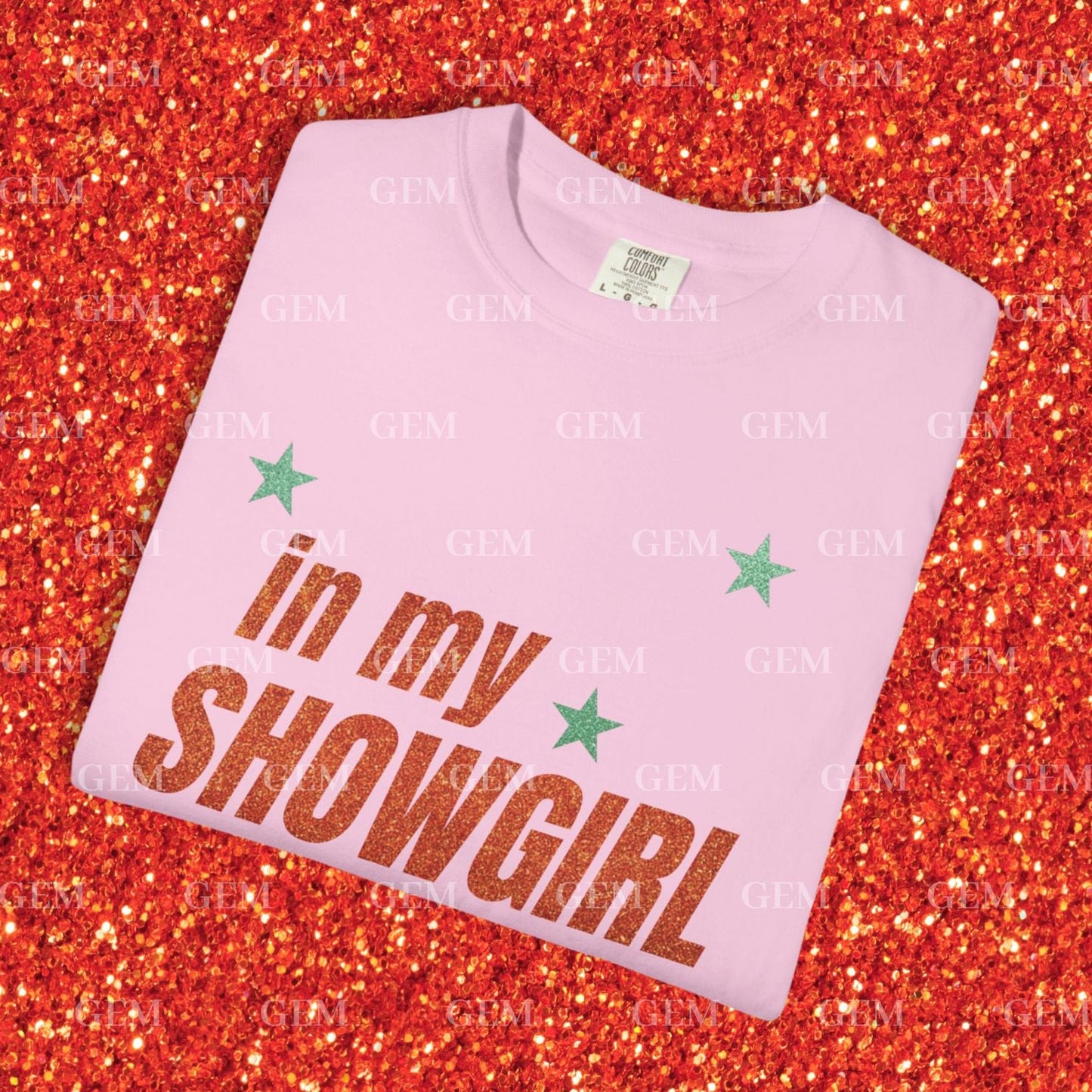 Pink t-shirt with 'in my SHOWGIRL' text on a glittery red background