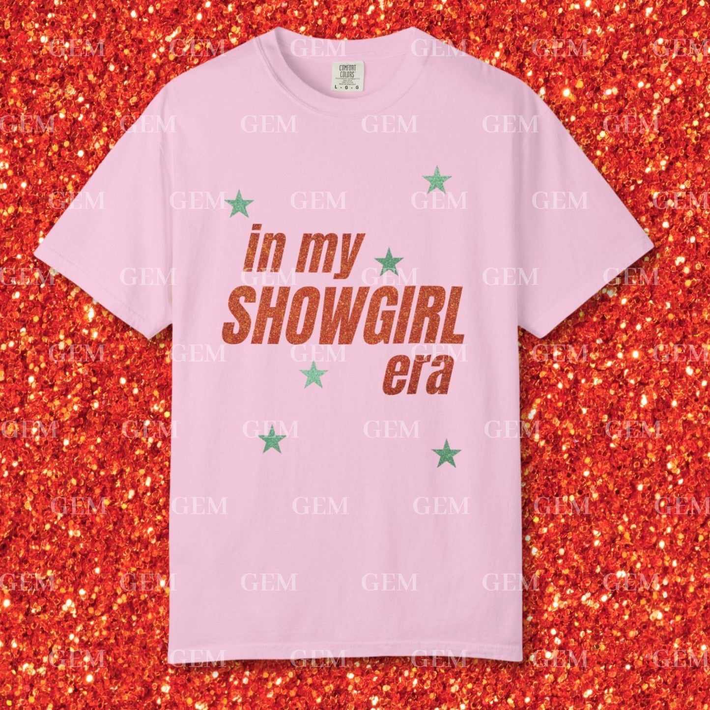Pink t-shirt with 'in my SHOWGIRL era' text on a glittery red background